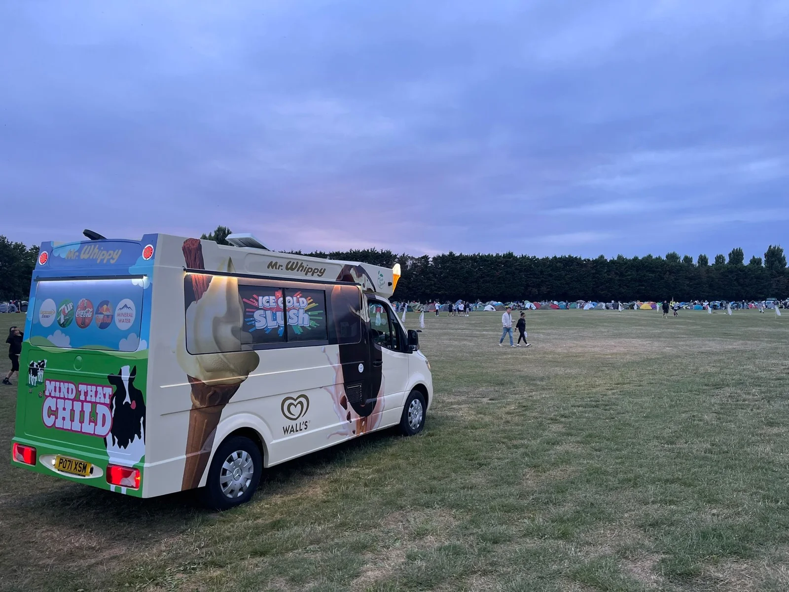 A Kreamy Delights ice cream van on a field at dusk