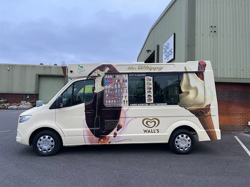 The serving side of the cream Kreamy Delights ice cream van, with its menu board and hatch